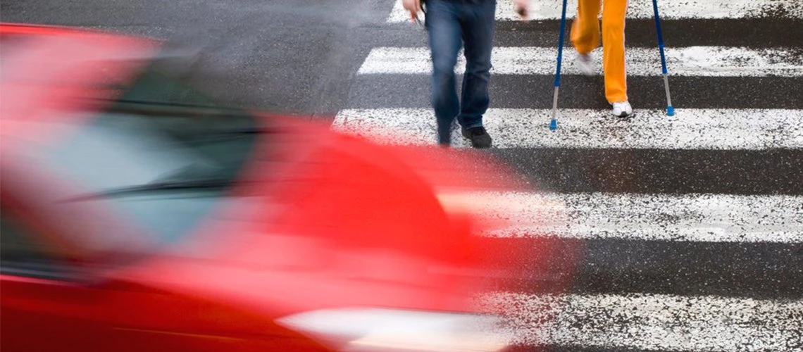 Pedestrians walking in a crosswalk as a car speeds by