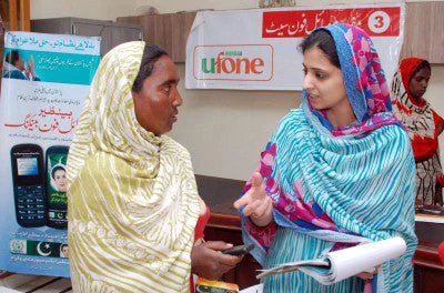 In Pakistan, Salma Riaz, right, shows Saba Bibi how to use her new cell phone to receive payments. © Muzammil Pasha/World Bank