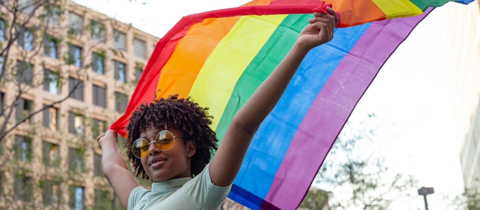 Persona afrodescendiente sosteniendo una bandera de la comunidad LGBTI