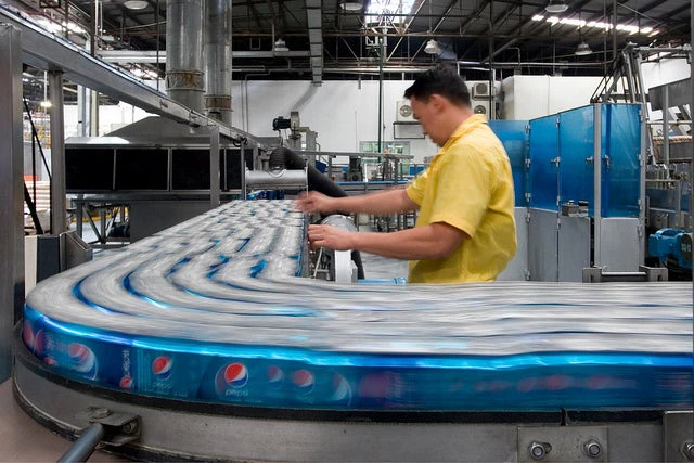 A quality controller inspects products on a conveyor belt before they are packaged.