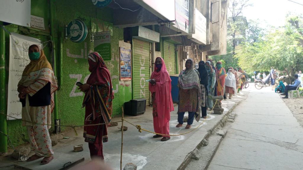 Beneficiaries practice social distancing while waiting to receive emergency cash transfers