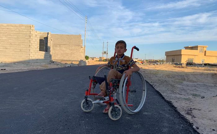 Qutab appears on a new road in his wheelchair.