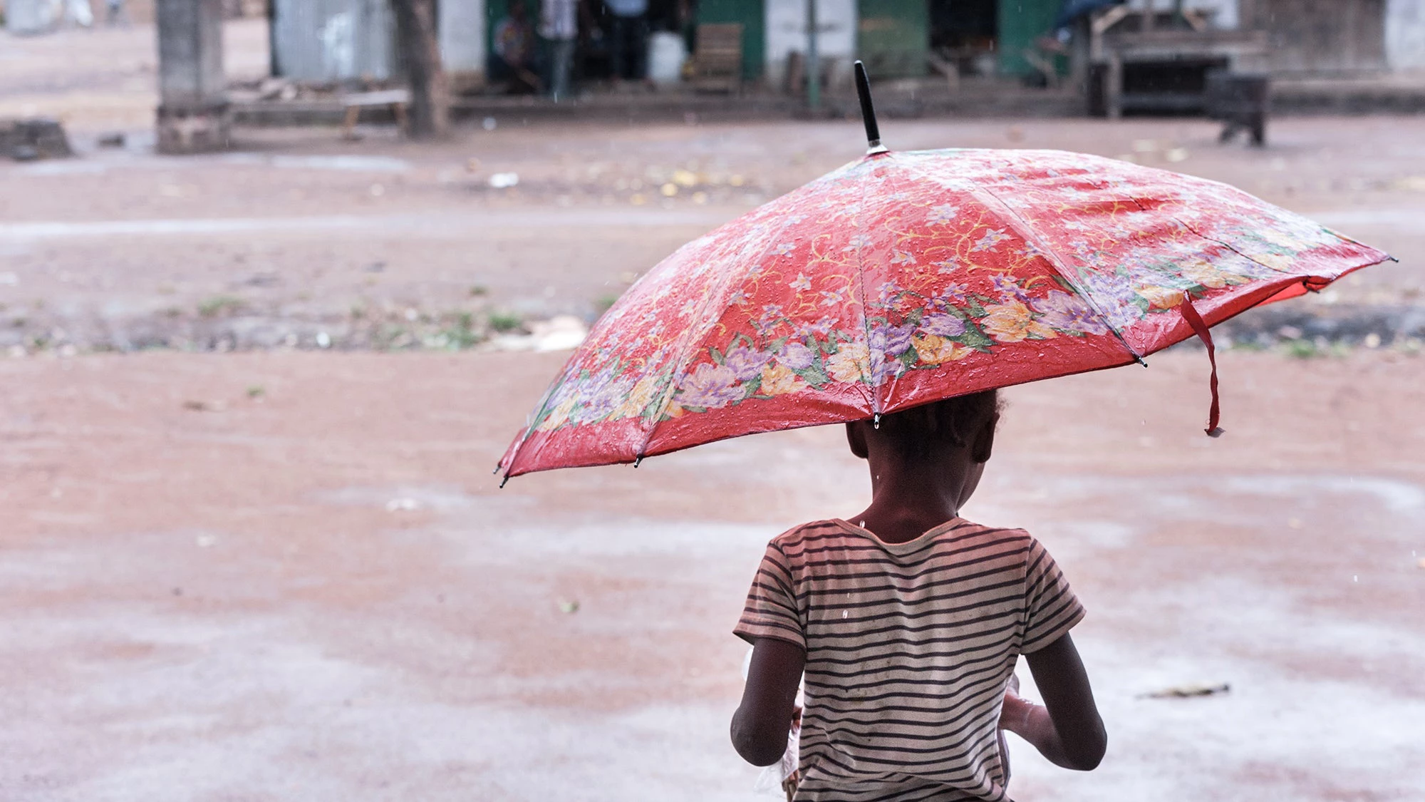 An internally displaced child walks in the rain in Kouango in the Central African Republic. © UN Photo/ Catianne Tijerina