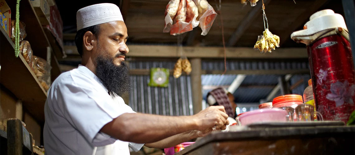 A tea stall owner makes tea in his shop at night in Bangladesh.