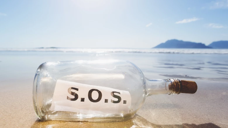 SOS message in glass bottle washed up on beach shore