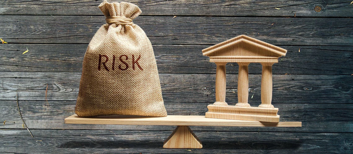 A money bag with the word Risk and a bank building on each side of a seesaw | © shutterstock.com (modified)