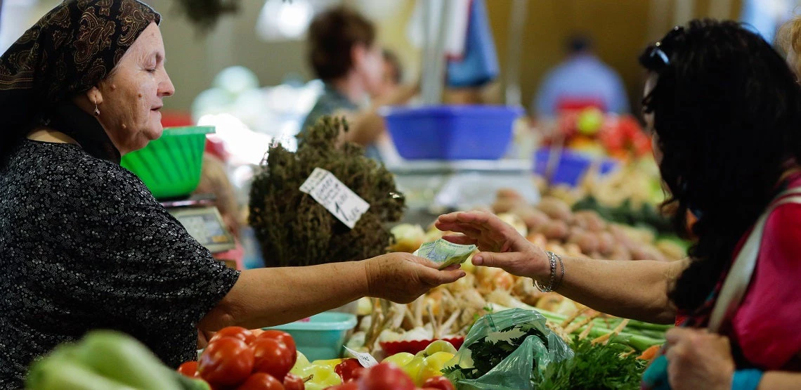 a woman buying vegetables from a stand in Obor market in Bucharest, Romania.