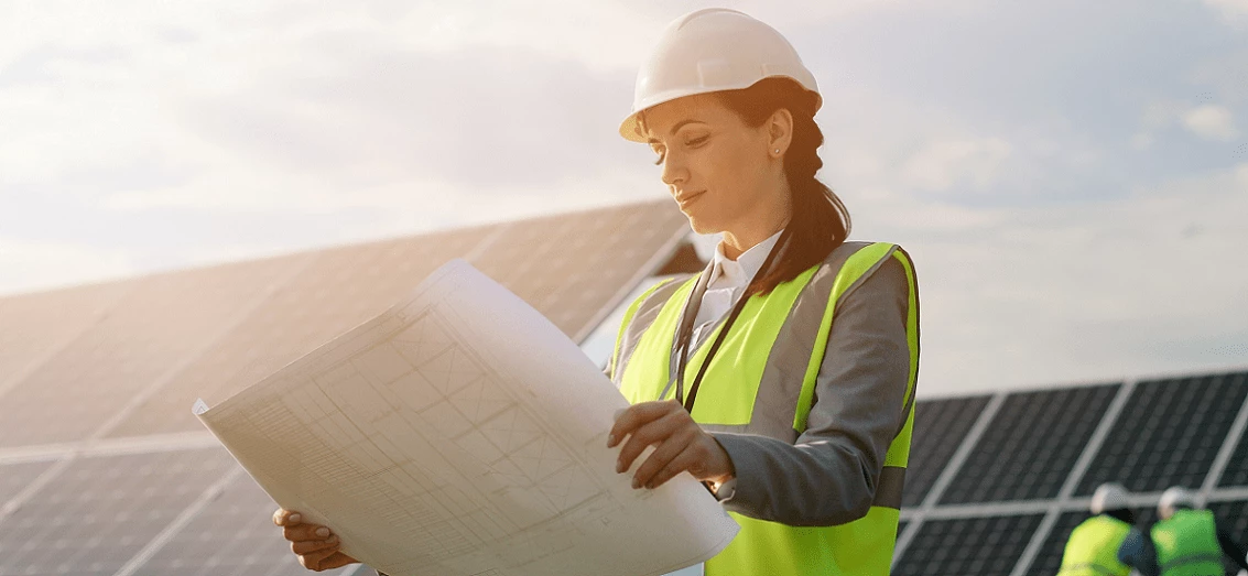 Female engineer looking at paper plans for solar panels