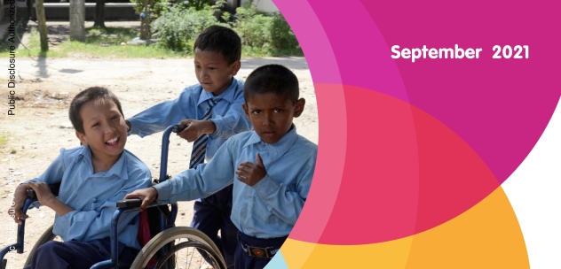 photo of three young kids in school uniform in a park. One of them is sitting on a wheelchair.