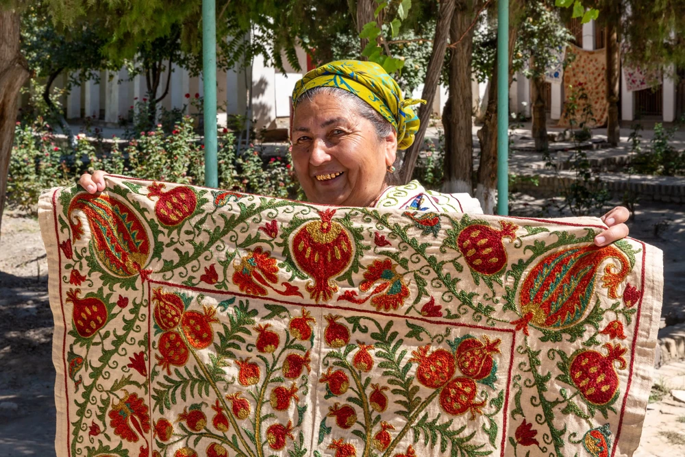 Bukhara.Uzbekistan- 09.18.2016 -Suzani - Central Asian embroidery. A woman with golden teeth sells a tablecloth (suzani). Bukhara. Uzbekistan