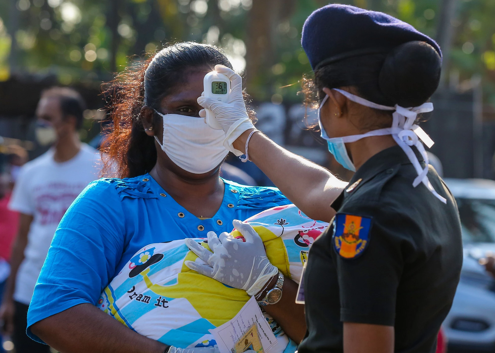 A woman officer checks fever of a woman carrying a child