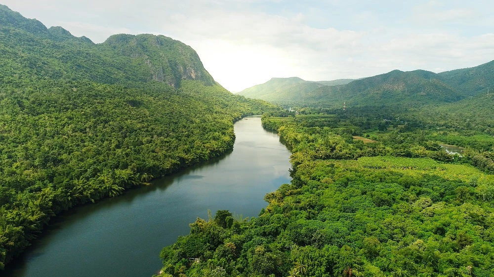 Beautiful natural scenery of river in southeast Asia tropical green forest with mountains in background, aerial view drone shot