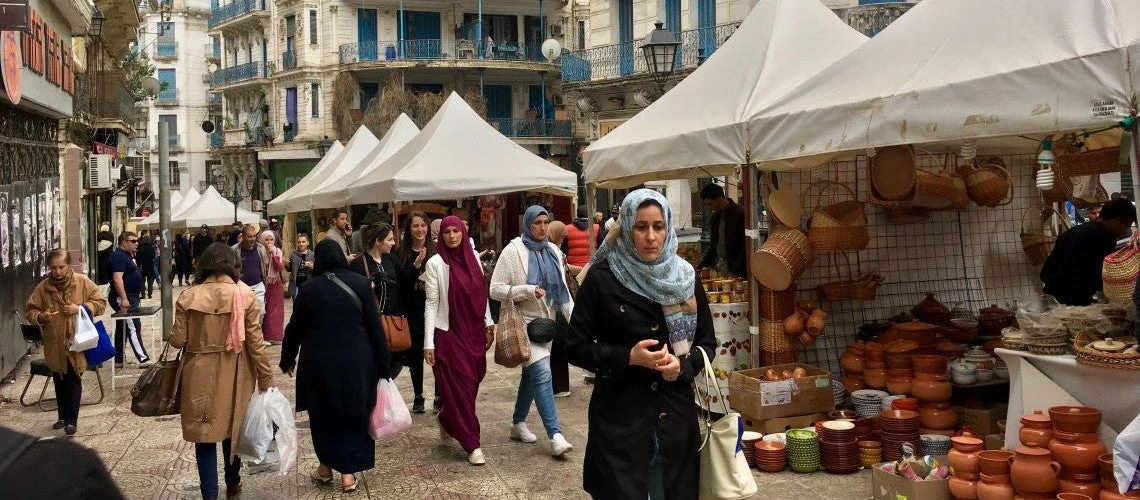 Shoppers walk through a market in Algeria.