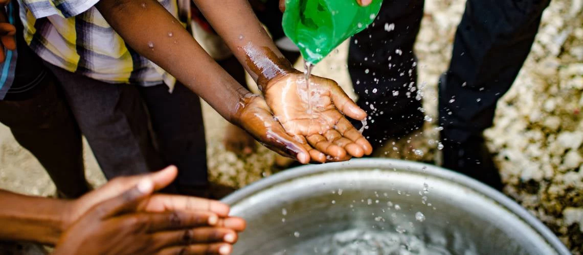 In Haiti, a child washes his hands from water delivered by the water truck. Photo: CMORimages/Shutterstock