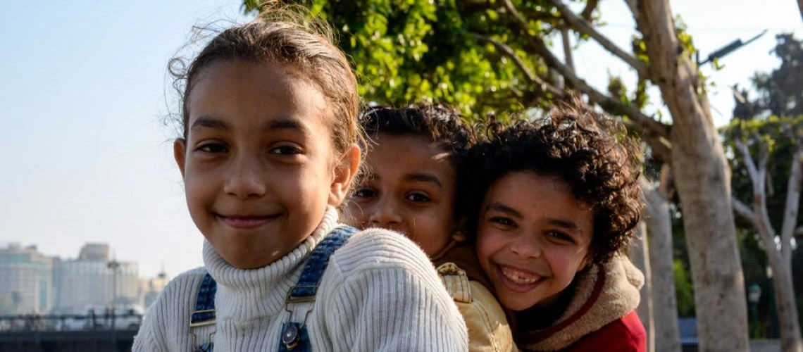 Three young Egyptian kids smile in the park in Cairo, Egypt.