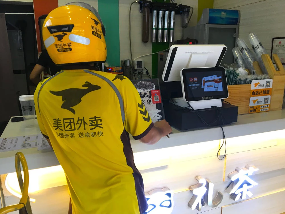 Food Delivery Service ?Meituan Waimai? staff picking up products at cafe.  Photo by: StreetVJ/Shutterstock