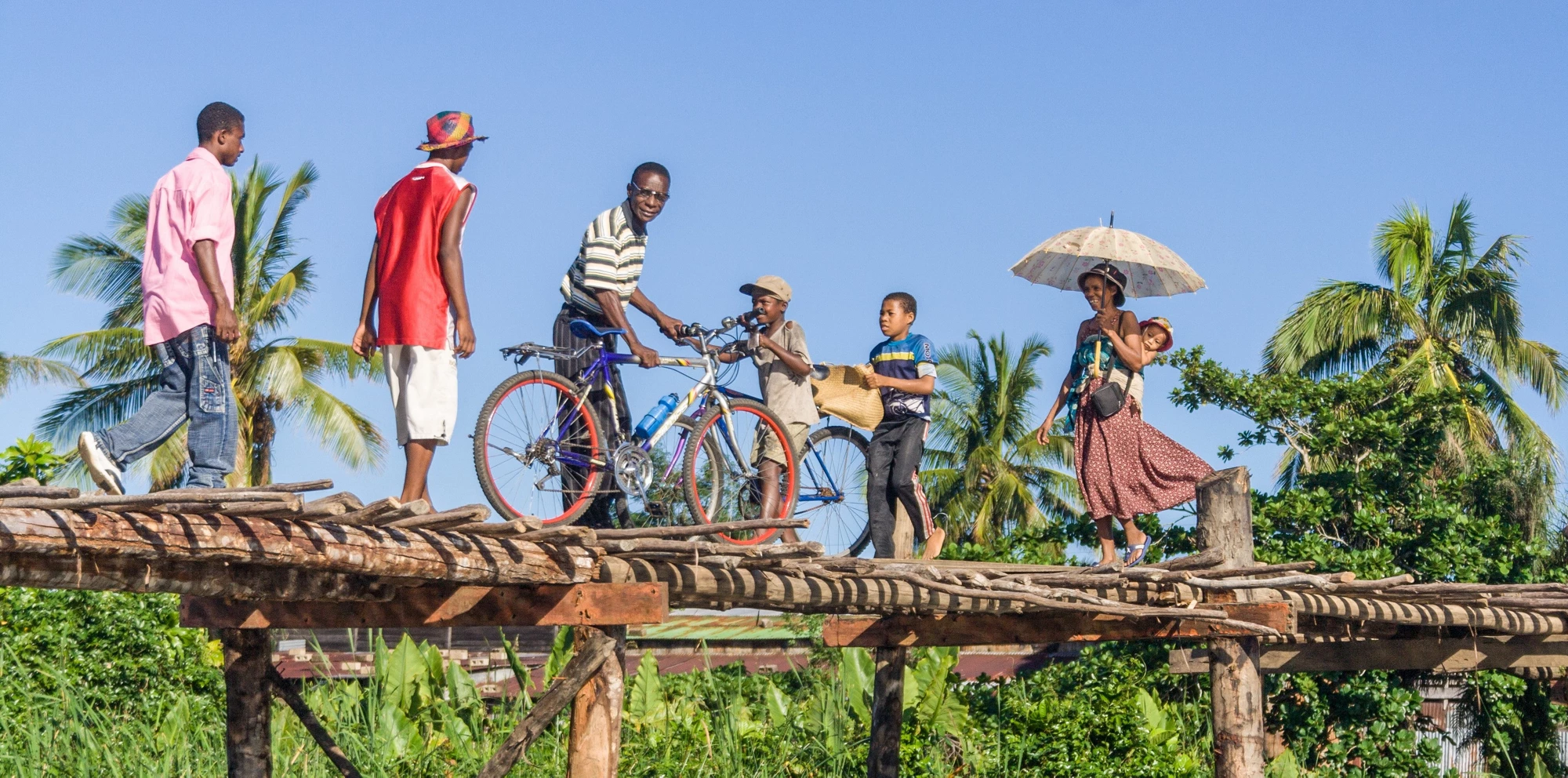 Malagasy people crossing the river by the wooden bridge.  © Shutterstock | Pierre-Yves Babelon