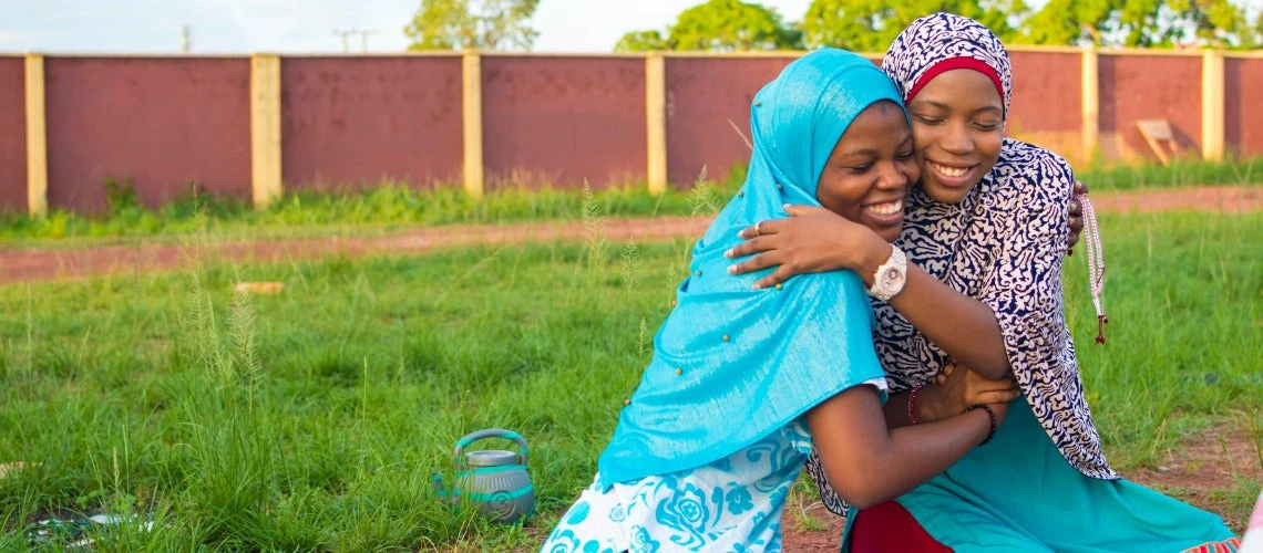 young african muslim girls hugging each other