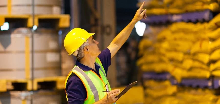 A shipping company worker counting pallets in warehouse before dispatching.