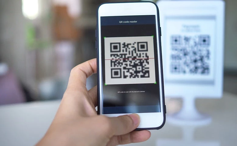 Women's hand uses a mobile phone application to scan QR codes in stores that accept digital payments without money and plastic tags on the table. QR code payment and cash technology concept