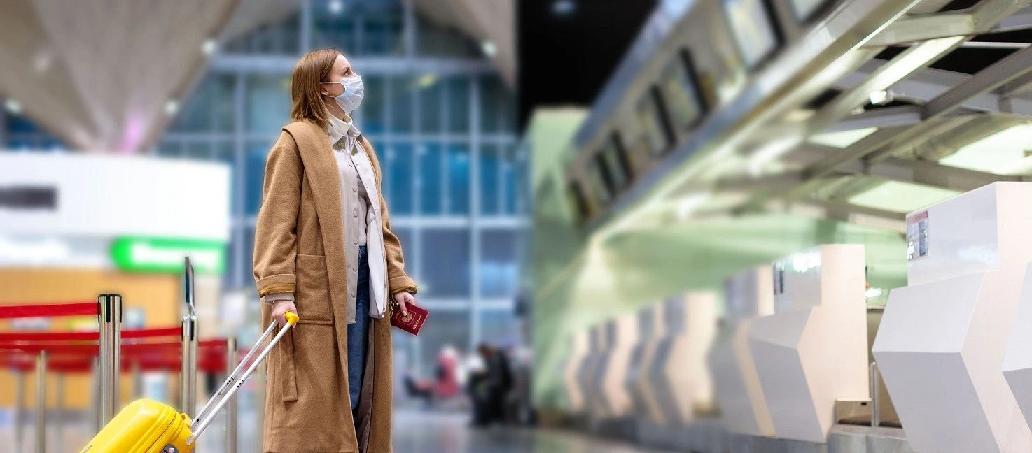 Une femme portant un masque devant une borne d'enregistrement à l'aéroport - Photo : DimaBerlin/Shutterstock