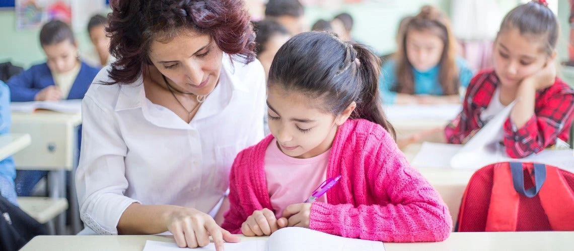 elementary schoolgirl and teacher in classroom