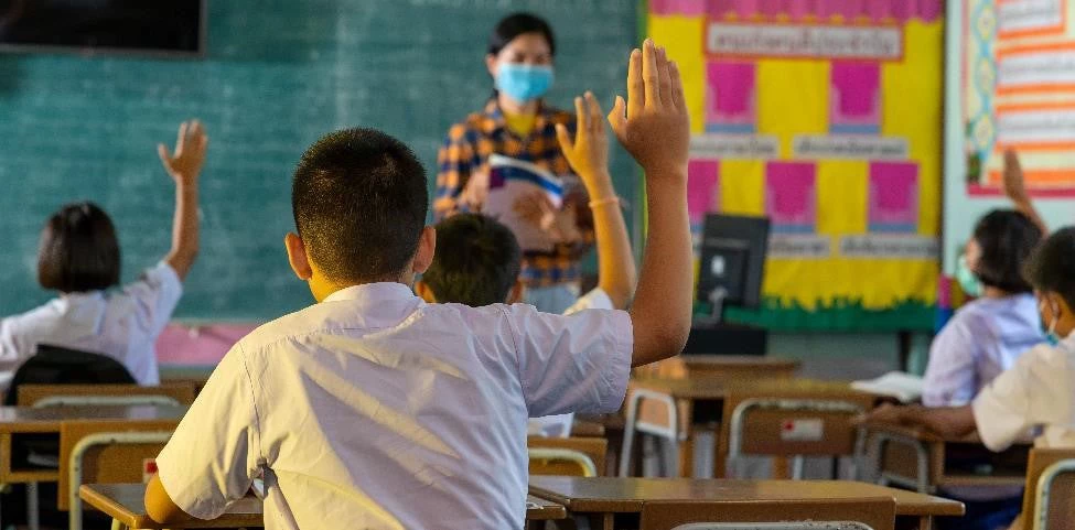 Des élèves et une enseignante portant des masques de protection dans une classe d'école primaire pendant la pandémie de COVID-19.