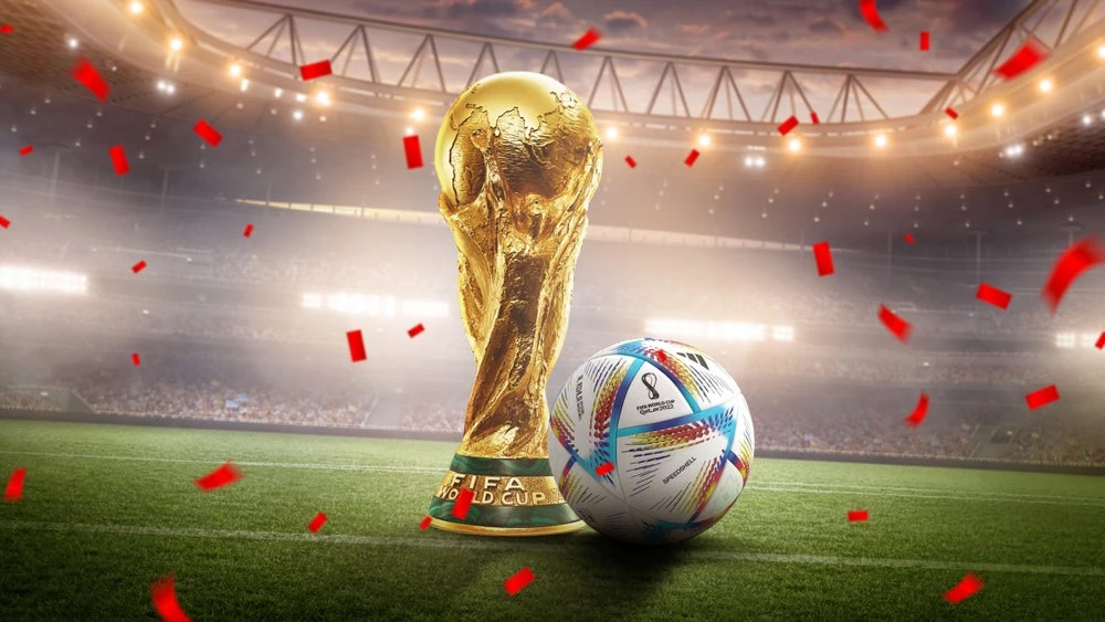 World Cup trophy next to FIFA football in stadium. (Shutterstock.com/Rehan Rasheed)