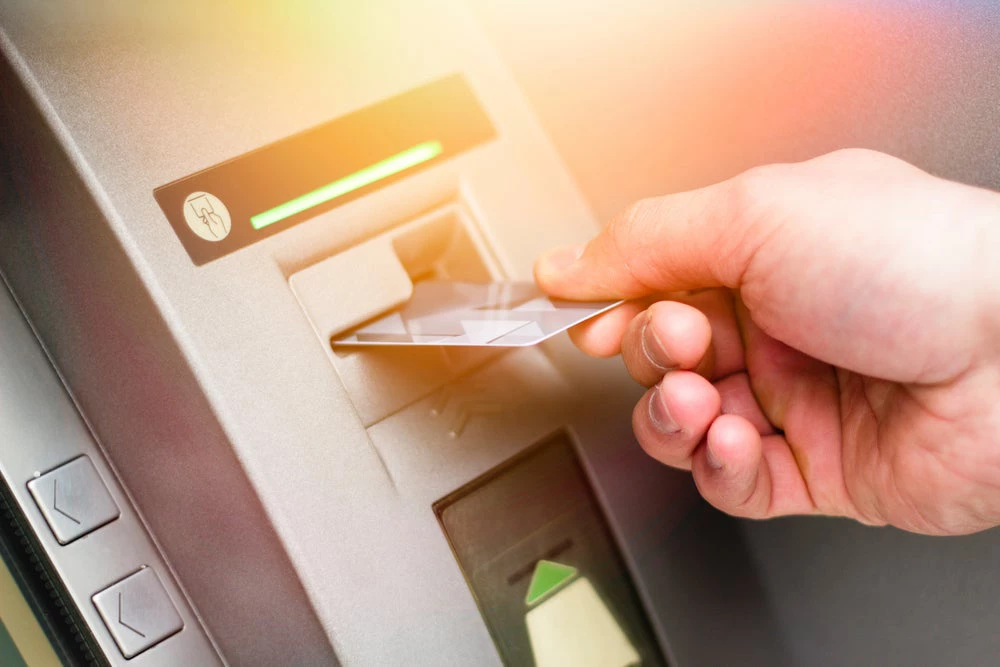 Hand taking money card out of machine. 