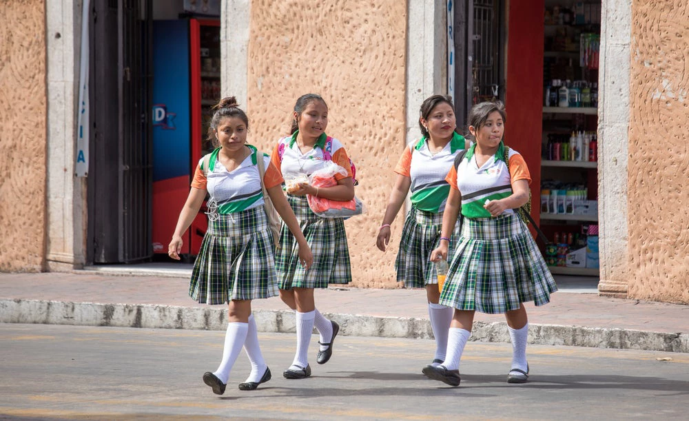 Valladolid, Mexico -Young girls in school uniform walking home after school hours. © Kertu/Shutterstock