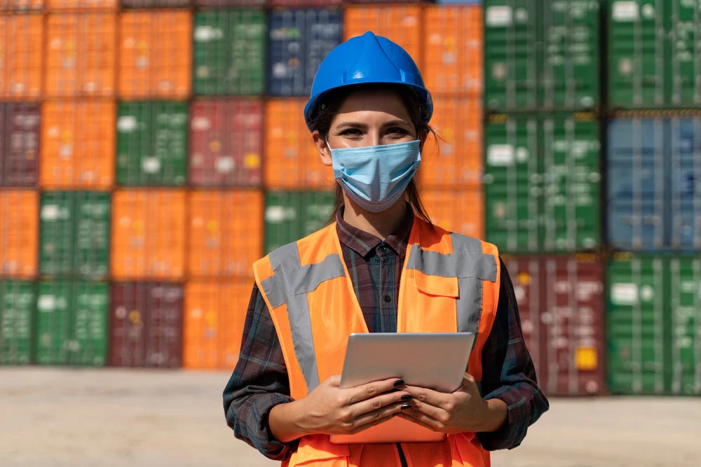 Woman logistics engineer in front of shipment containers.