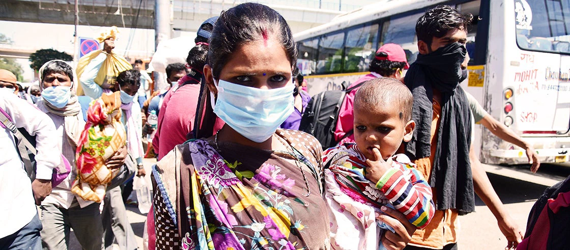 Une migrante avec un bébé porte un masque à la gare routière d'Anand Vihar de New Delhi, une mesure de prévention pendant le confinement du pays. Photo : rajput/SOPA Images/Shutterstock