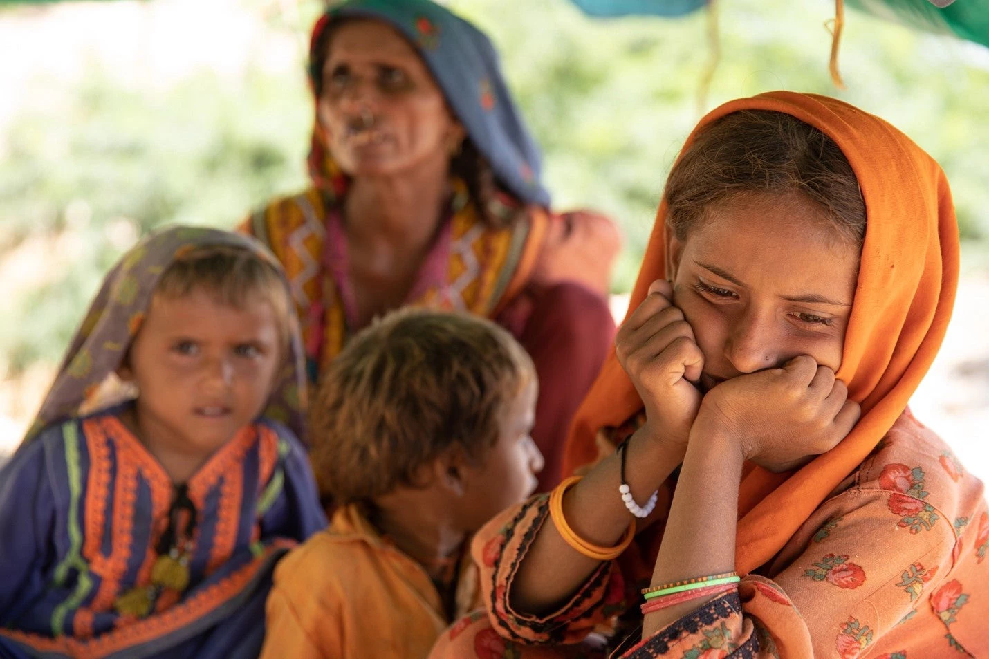 Three children from Sindh looking concerned and sitting with elderly woman