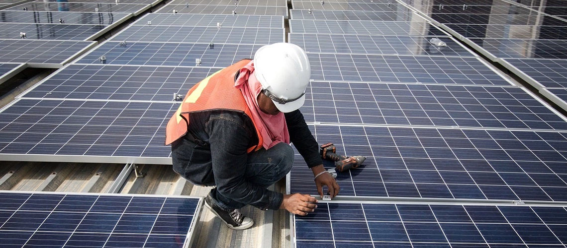 A technician installs solar panels on a factory roof in Bangkok, Thailand.