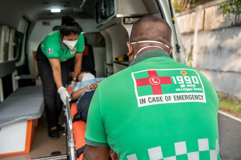 Paramedics loading a patient into an ambulance.