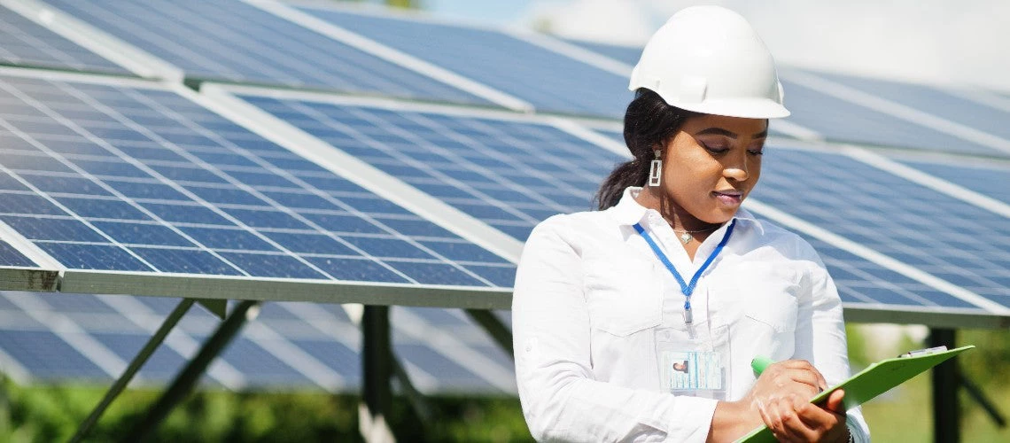 A black woman engineer at a solar station checks the maintenance of the solar panels.