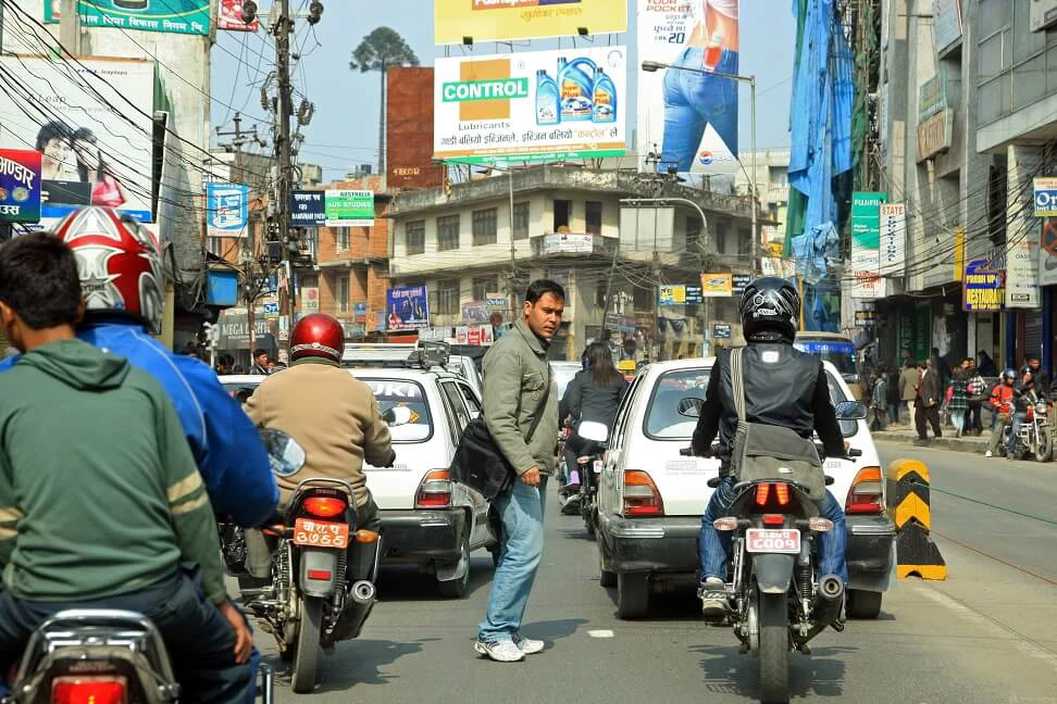 A pedestrian crossing a bustling street amidst rush hour in Kathmandu Nepal