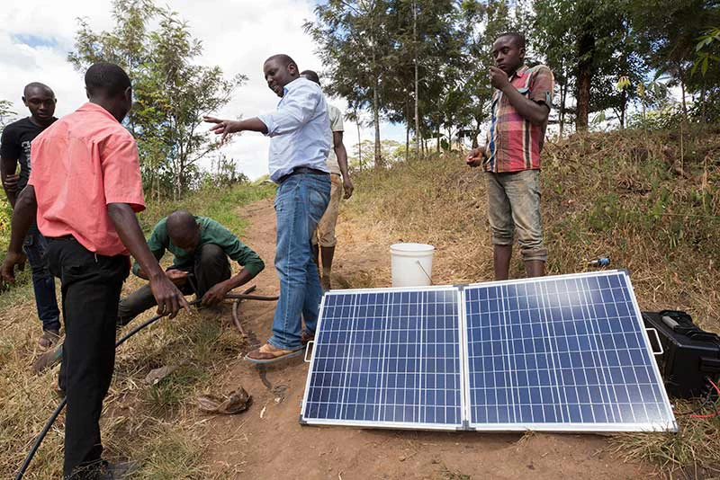 Charles Ngatia Kaombe, ingénieur agricole chez Sunculture, (habillé d'une chemise blanche) fait une démonstration d'un système d'irrigation par panneaux solaires, le long de la rivière Morie à Makuyu, au Kenya, le 12 février 2018. Photo © Dominic Chavez/IFC