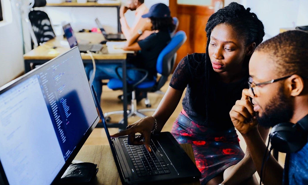 Woman and man look over computer screen together