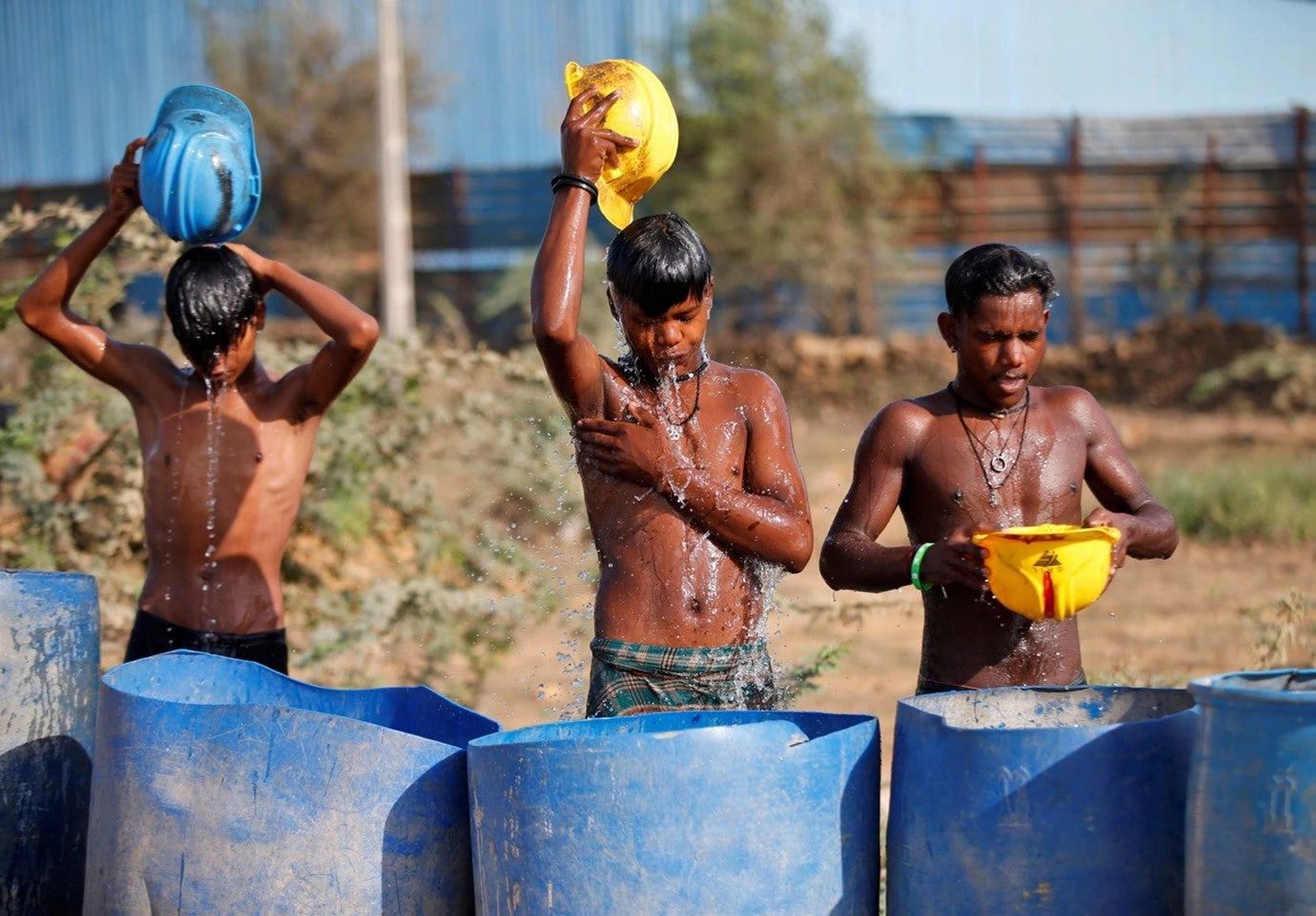 Workers at a construction site on the outskirts of Ahmedabad, India, try to cool themselves during the record-breaking heatwave earlier this year. Photo: Amit Dave / Alamy)