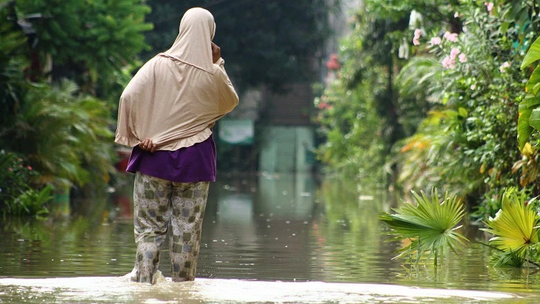 A Woman walk in high waters. Heavy rains caused floods in many areas around Bekasi