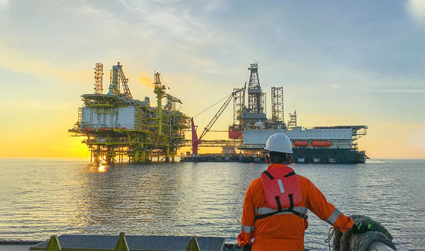 A crew member looks onto an oil platform at sunrise. 