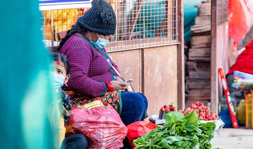 Personas que usan mascarillas y venden verduras en el mercado callejero durante la pandemia de COVID-19 en Katmandú.