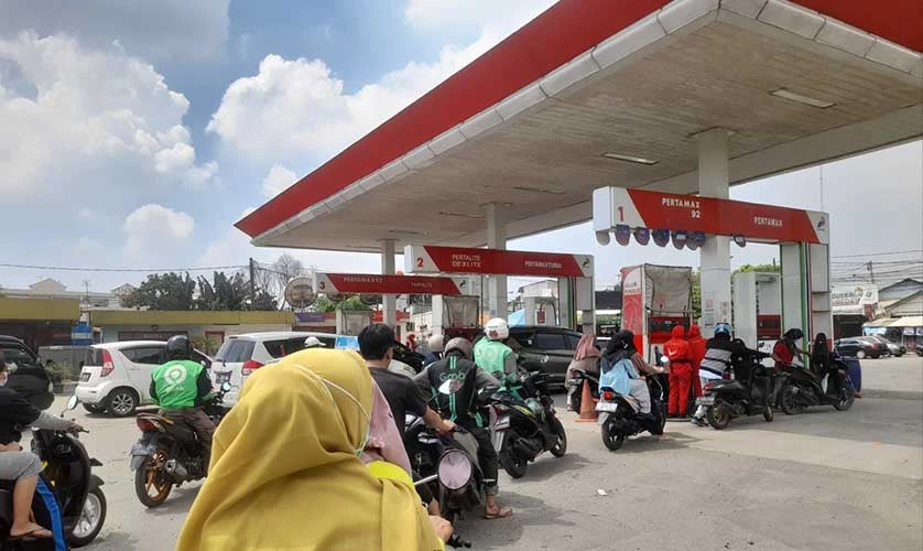 Photo of motorcyclists lining up to refuel at a gas station.