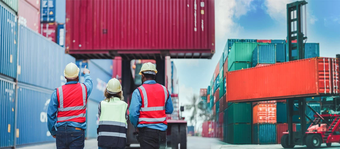 Industrial worker works with co-worker at overseas shipping container yard. Logistics supply chain management and international goods import and export concept 