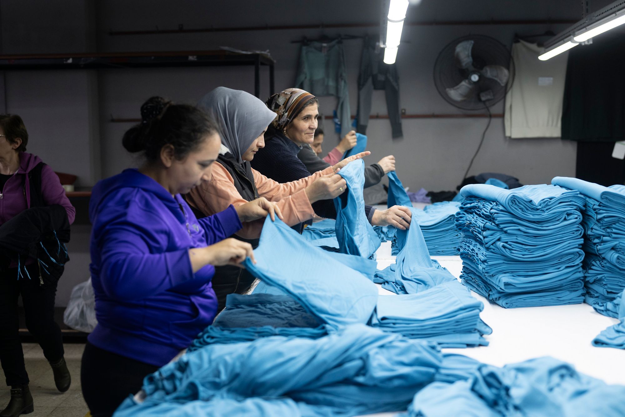 Des ouvrieres plient des vêtements qui ont été teints et sont prêts à être expédiés. 