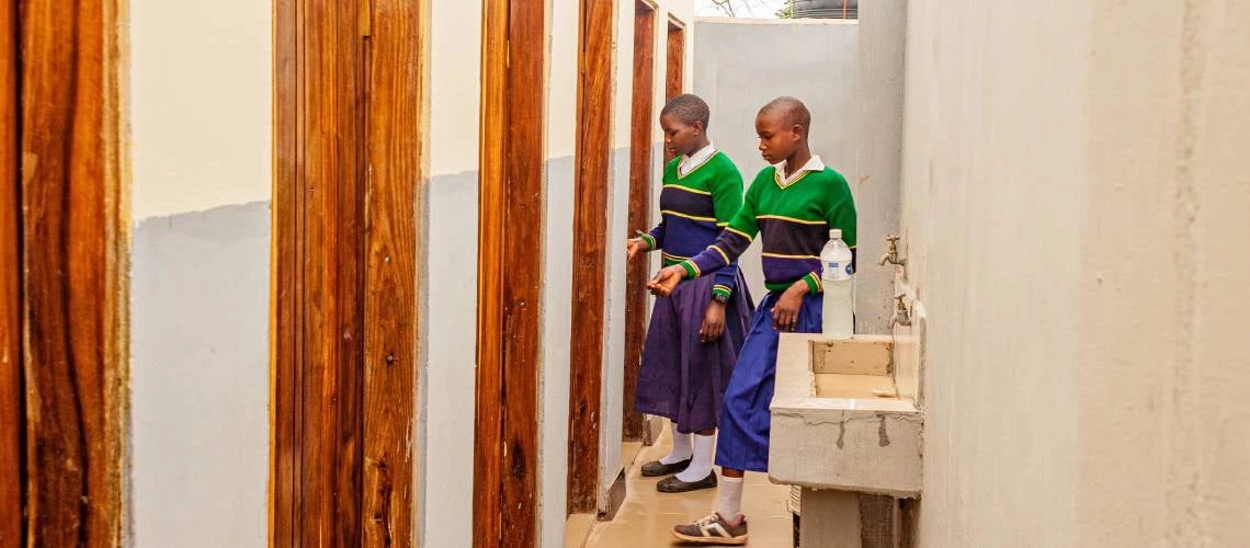 فتيات يستخدمن حمام تم بناؤه بدعم من برنامج توفير خدمات المياه والصرف الصحي في المناطق الريفية في تنزانيا