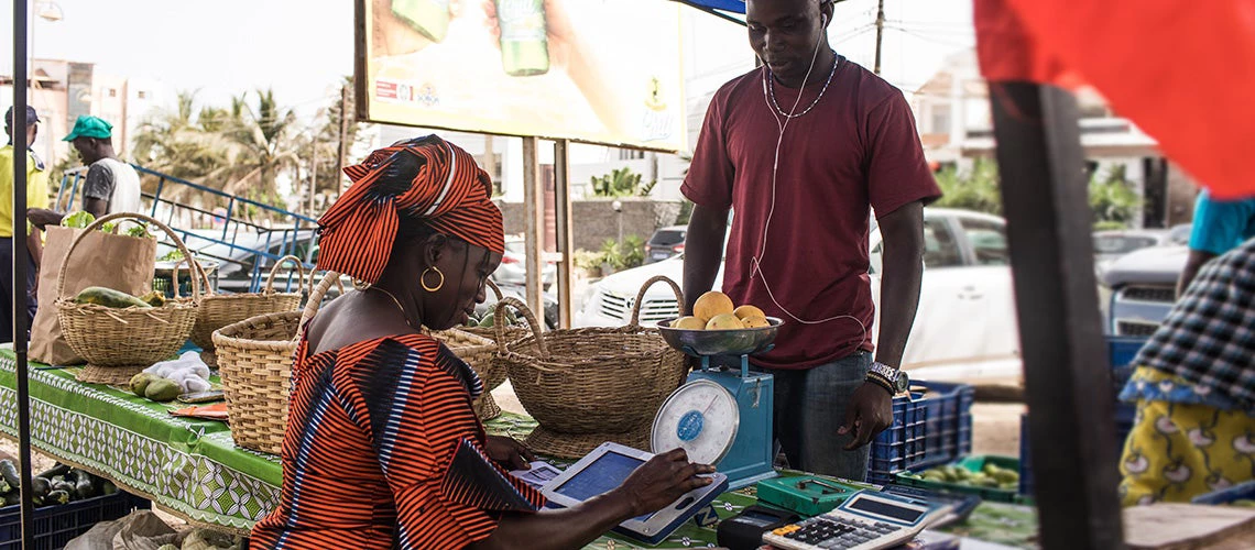 Using smart technology to manage sales: Binta is filling the vegetables she sells on her Weebi tablet. | © Vincent Tremeau / World Bank