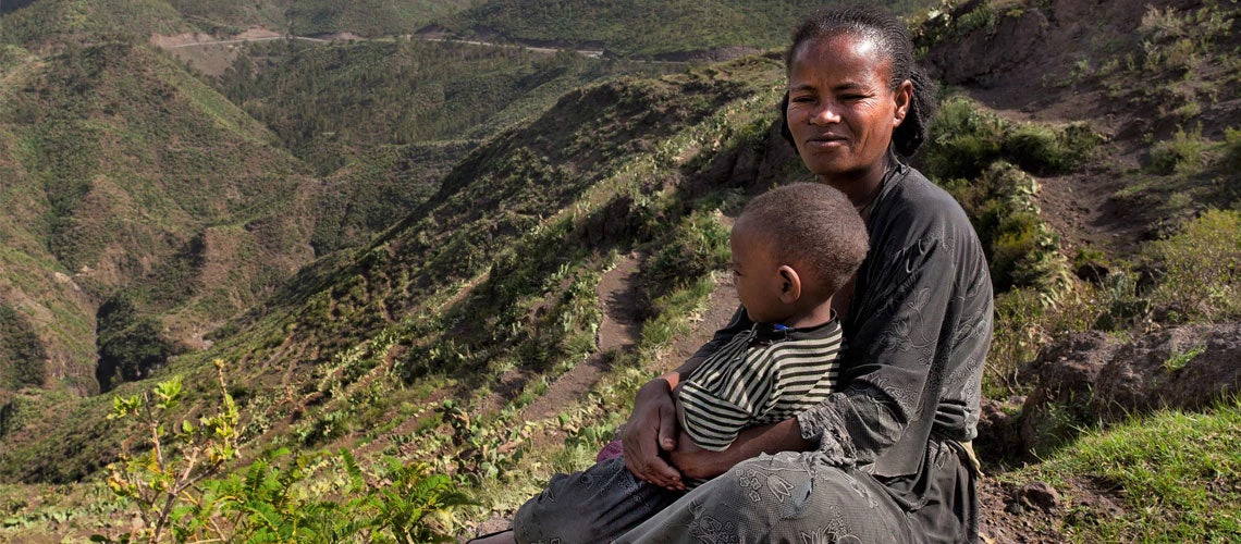 Mother and child sitting in front of newly terraced land in Ethiopia. Photo: Borgarello/ World Bank.