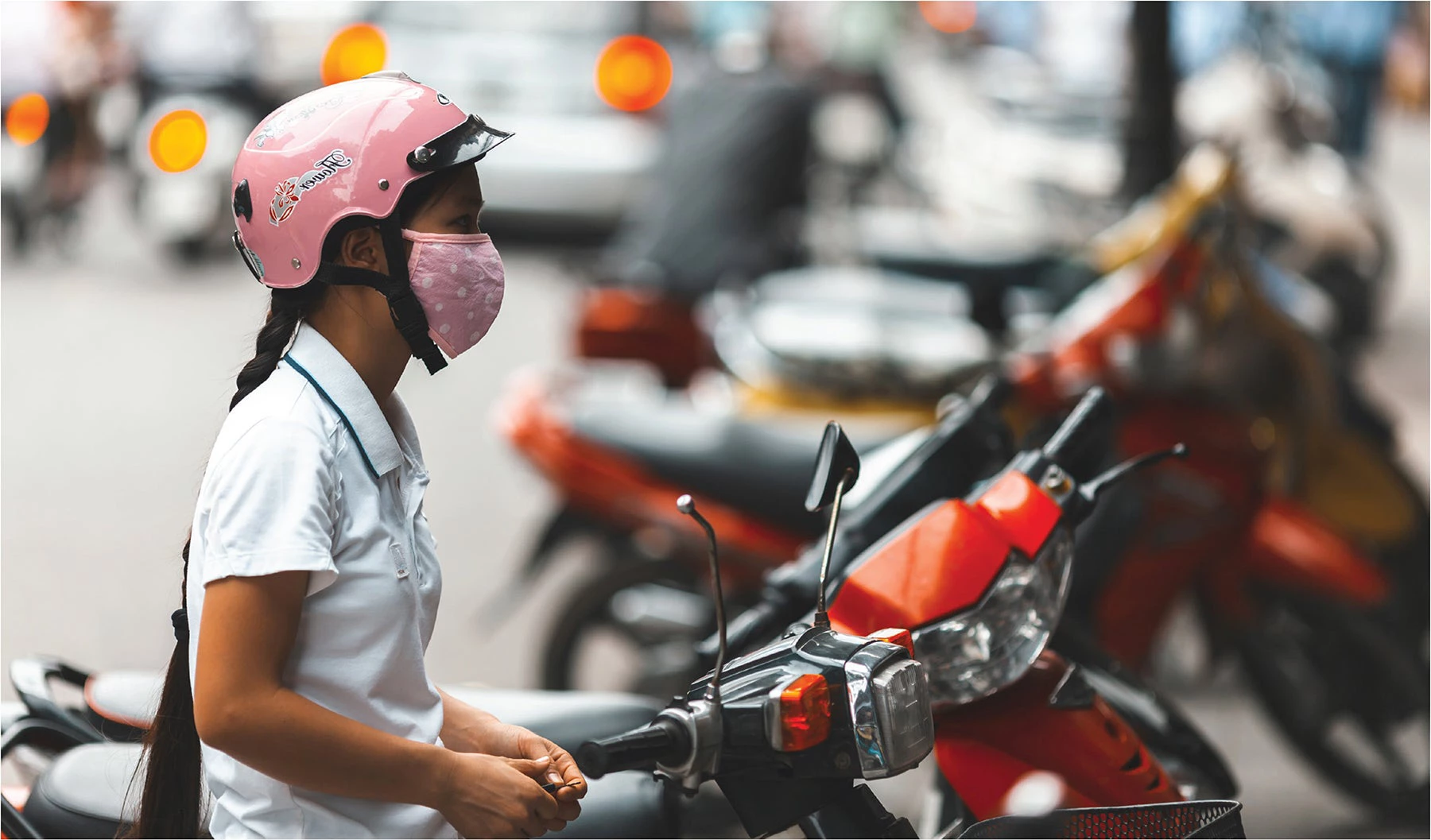 Woman waiting on her motorbike in Hanoi, Vietnam. Photo: Beboy/Adobe Stock